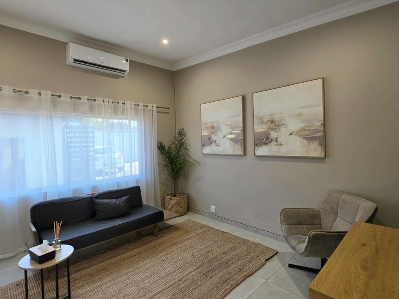 A well-maintained office space featuring neutral wall tones, tiled flooring, and a wall-mounted split-system air conditioning unit.