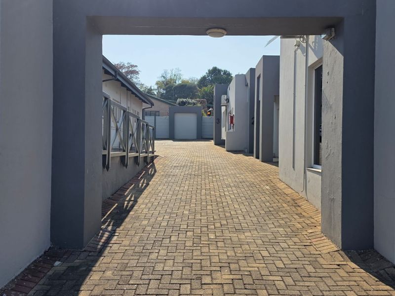 A paved driveway leading through a covered entrance into an office complex with multiple individual units.
