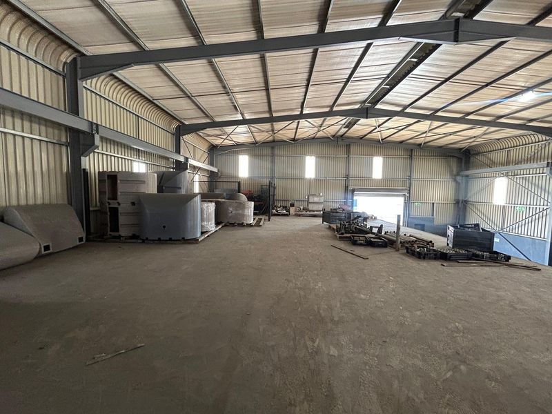 Spacious industrial warehouse featuring a steel portal frame, corrugated metal walls, and a durable concrete floor with large access points.