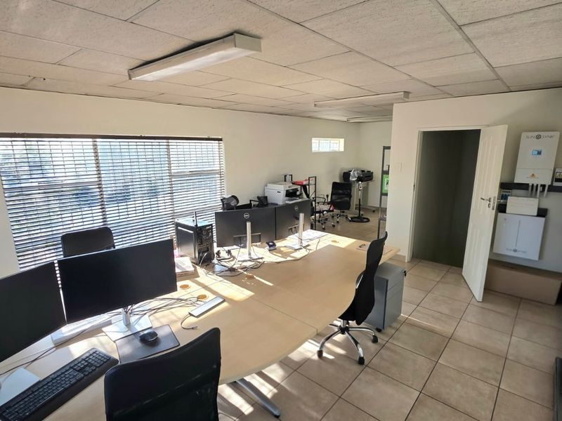 A functional office space featuring tiled flooring, a suspended ceiling, air conditioning, and an integrated inverter system for power backup.