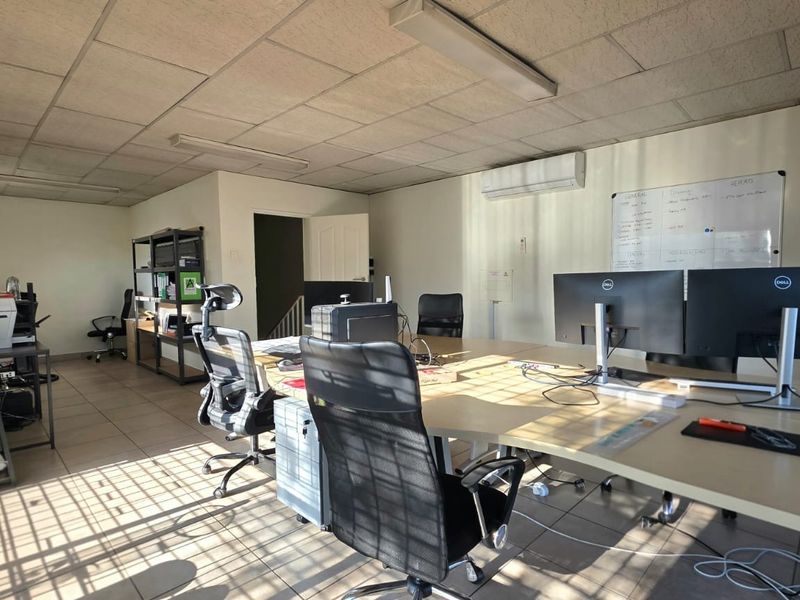 A functional office space featuring tiled flooring, a suspended ceiling, and an integrated air conditioning unit.
