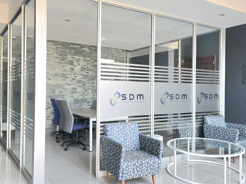Modern office space featuring glass partition walls, a stone veneer feature wall, and polished tile flooring, creating a professional and bright work environment.