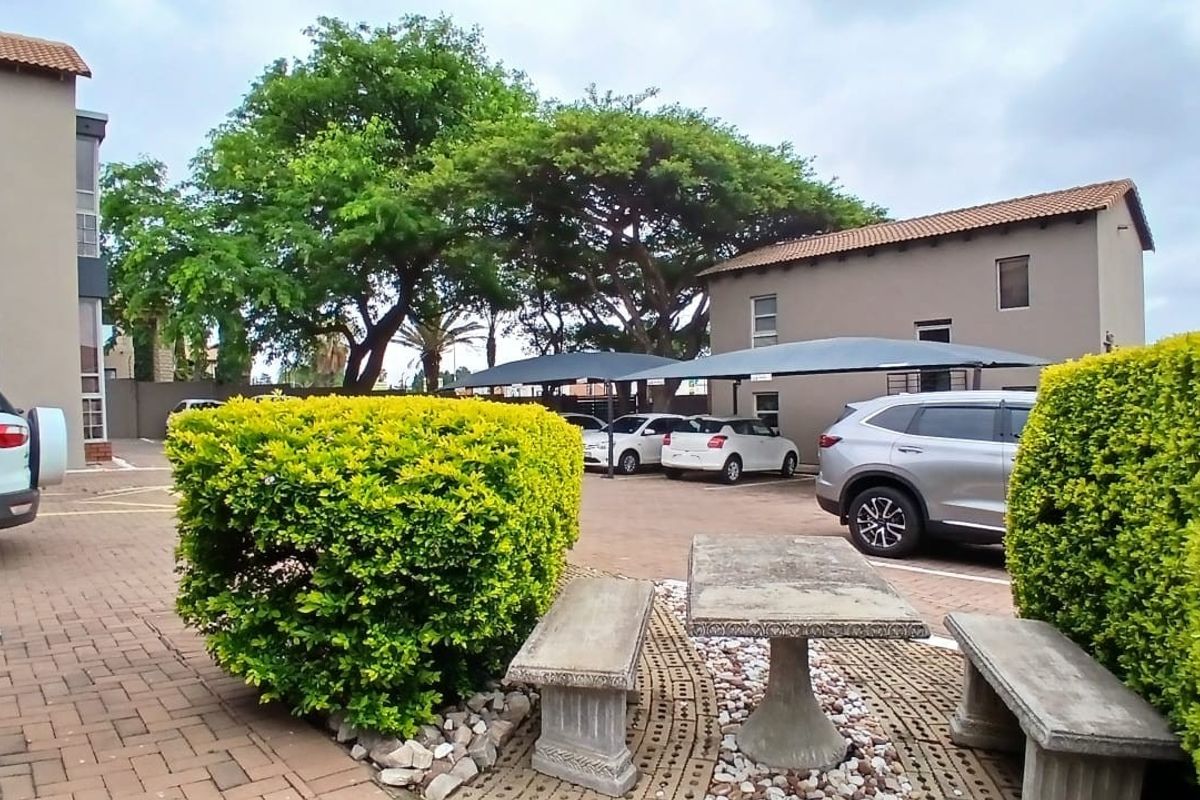 Exterior view of the office complex featuring a paved parking area with shade cloth carports and established garden landscaping.
