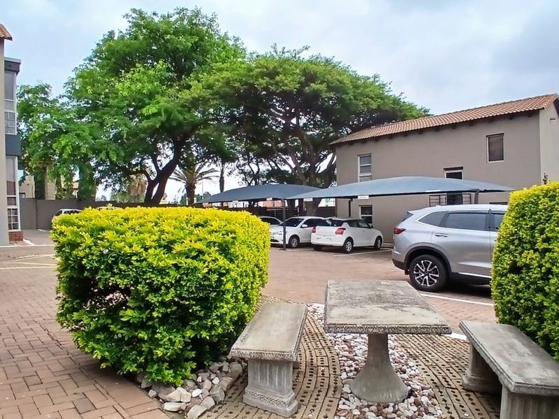 Exterior view of the office complex featuring a paved parking area with shade cloth carports and established garden landscaping.