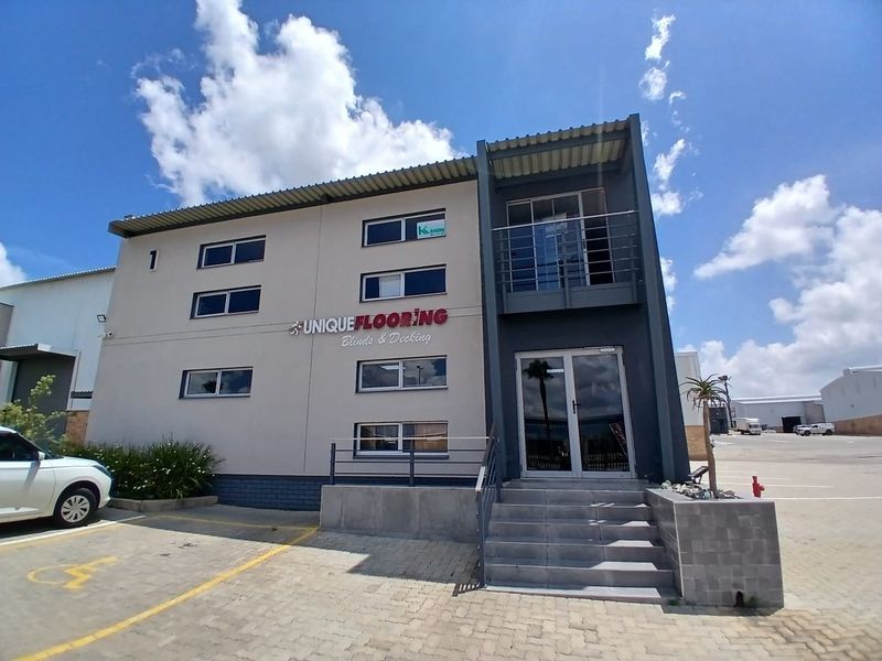Front elevation of a modern commercial office building featuring a paved parking area, concrete entrance stairs, and aluminum-framed windows.