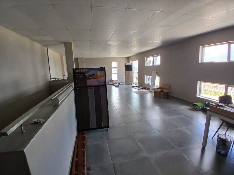Spacious open-plan office area featuring large windows, modern tiled flooring, and a suspended ceiling, offering a bright and versatile workspace.