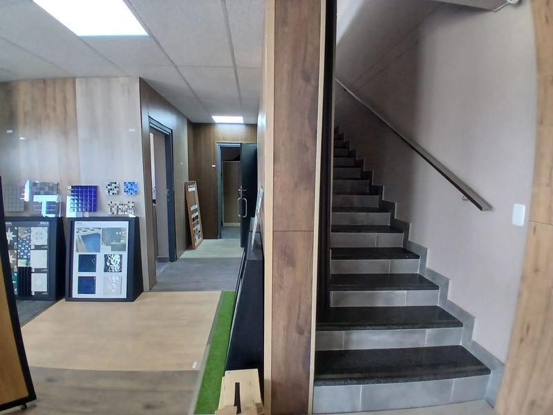 Modern office interior featuring a staircase with dark stone treads, wood-look wall paneling, and recessed ceiling lighting.