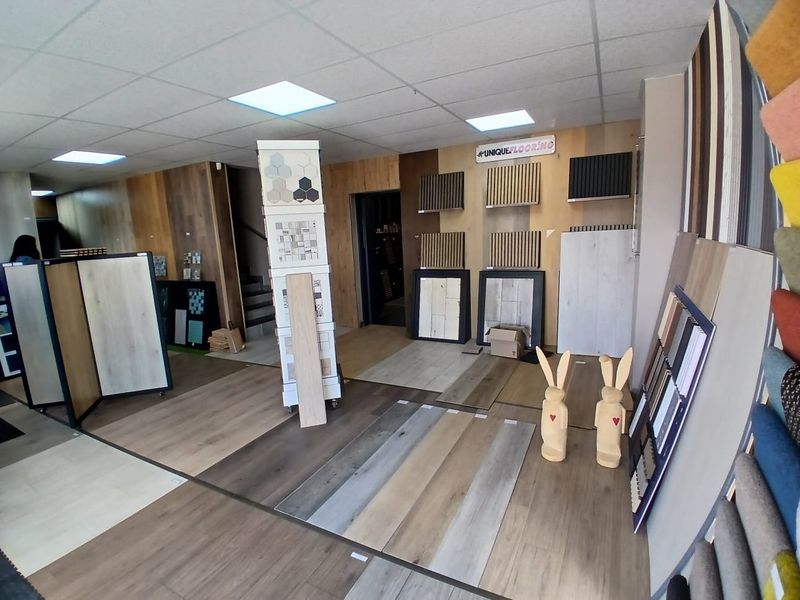A commercial showroom space featuring various laminate flooring samples, wall-mounted displays, and recessed ceiling lighting.
