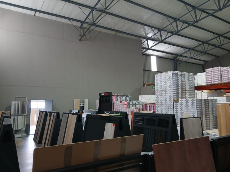 Spacious industrial utility area featuring high-bay ceilings with exposed steel trusses and durable concrete flooring, suitable for storage or commercial operations.