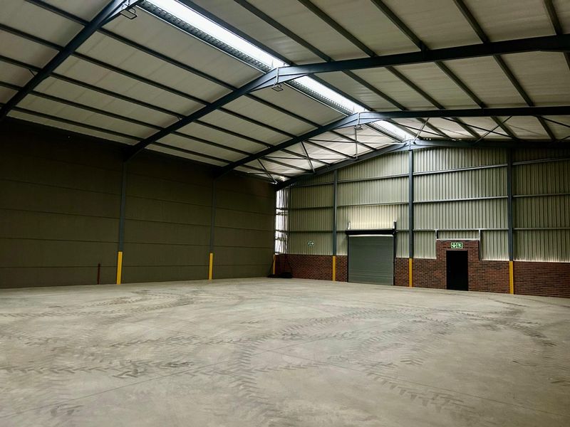 Spacious industrial warehouse unit featuring high ceilings, steel portal frame construction, concrete flooring, and a large roller shutter door for easy access.
