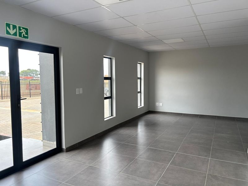 A clean, modern, and empty office space featuring neutral grey walls, large windows, tiled flooring, and a suspended ceiling, ready for immediate commercial use.