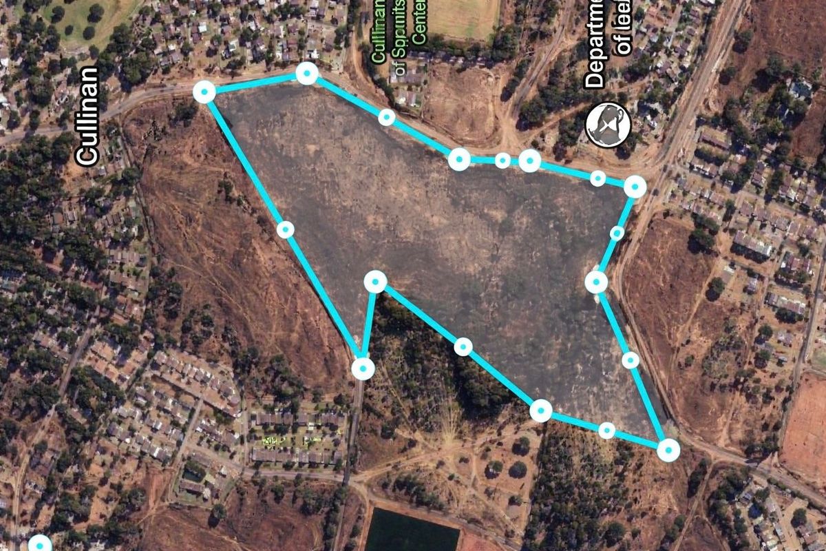 Aerial view of a large vacant commercial land parcel with marked boundaries, situated in a developed urban area.