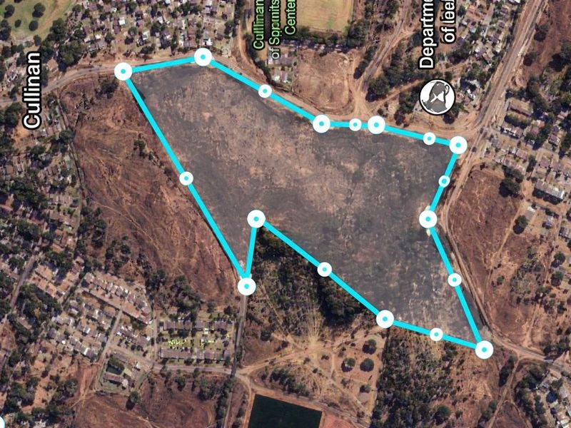 Aerial view of a large vacant commercial land parcel with marked boundaries, situated in a developed urban area.