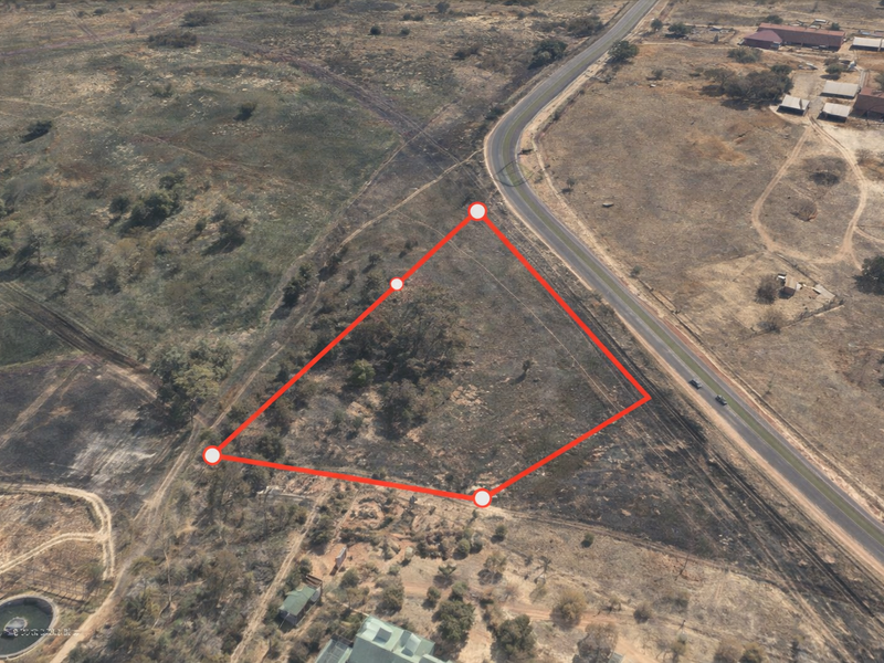 Aerial view of a vacant commercial land parcel with road frontage, highlighting the property boundaries.