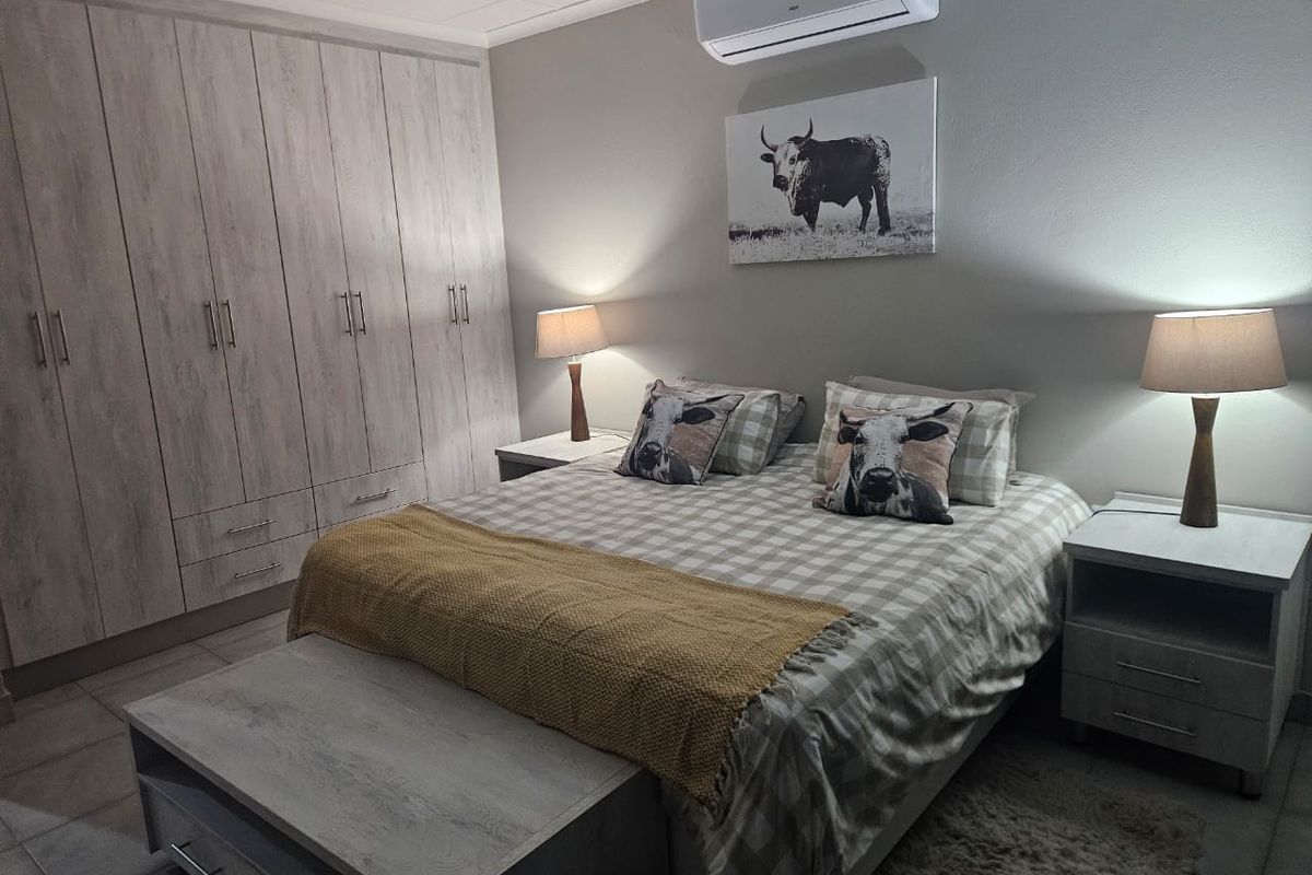 A well-maintained bedroom featuring built-in cupboards, tiled flooring, and a wall-mounted split-system air conditioner.