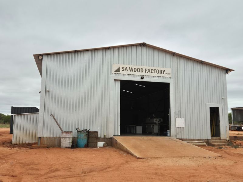 Industrial farm workshop building featuring corrugated metal cladding, a large sliding entrance door, and a concrete loading ramp.