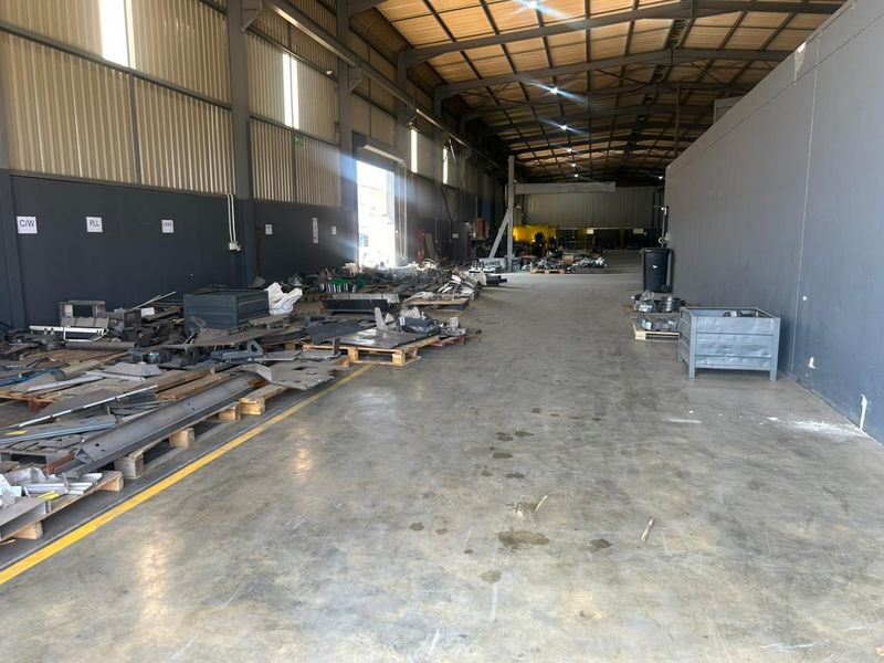 Spacious industrial warehouse unit featuring concrete flooring, high-bay lighting, and a robust steel portal frame structure suitable for manufacturing or storage operations.