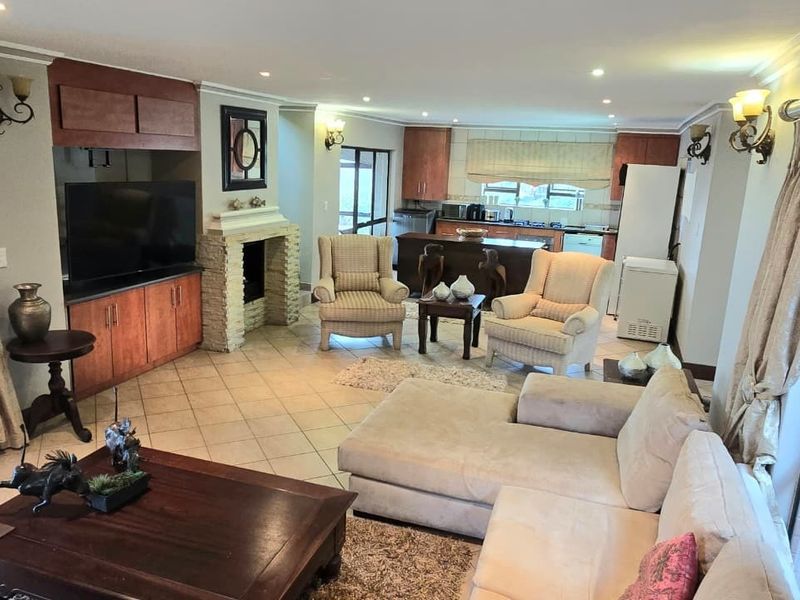 Spacious open-plan living area featuring a stone-clad fireplace, built-in cabinetry, and a functional kitchen with a central island.