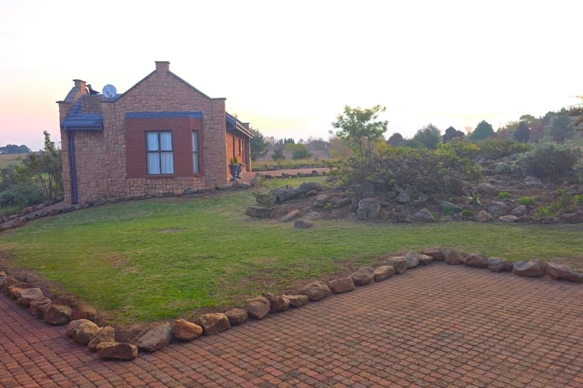 A view of the lodge exterior featuring stone and brick masonry, a paved driveway, and a well-maintained garden setting.