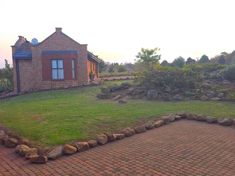 A view of the lodge exterior featuring stone and brick masonry, a paved driveway, and a well-maintained garden setting.