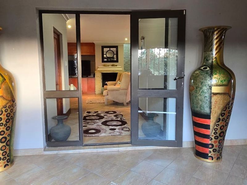 A covered patio area featuring tiled flooring and a glass door entrance leading into a living space with a built-in fireplace.