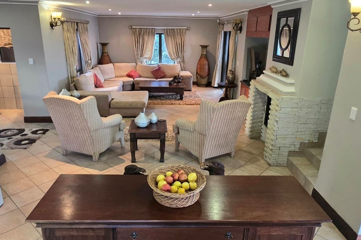 Spacious living area featuring a prominent stone-clad fireplace, tiled flooring, and recessed lighting, creating a comfortable and inviting atmosphere.