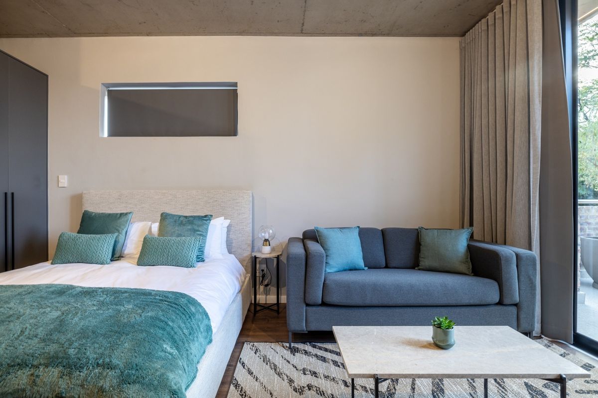Modern bedroom featuring an exposed concrete ceiling, built-in wardrobe, and large sliding glass doors providing natural light and access to the outdoors.