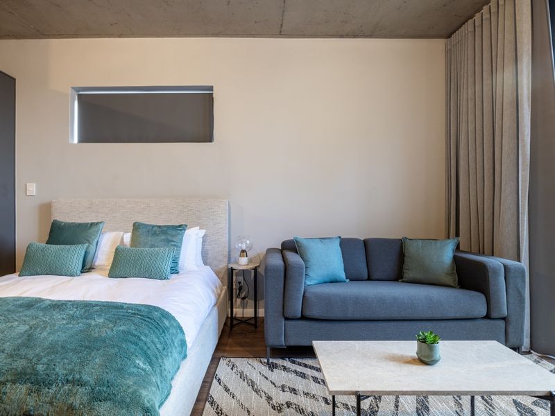 Modern bedroom featuring an exposed concrete ceiling, built-in wardrobe, and large sliding glass doors providing natural light and access to the outdoors.