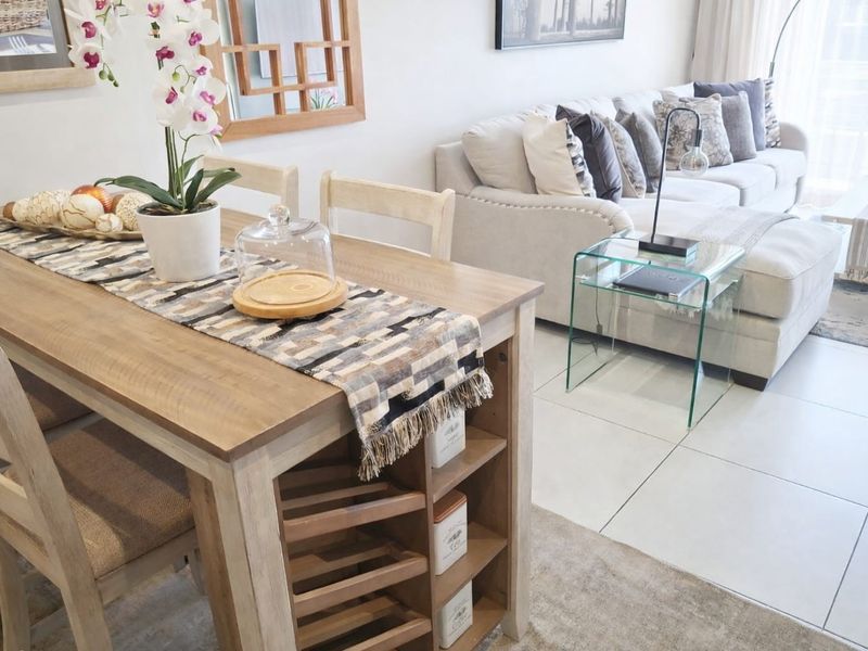 A bright open-plan living and dining area featuring neutral tiled flooring and a modern, well-maintained interior layout.