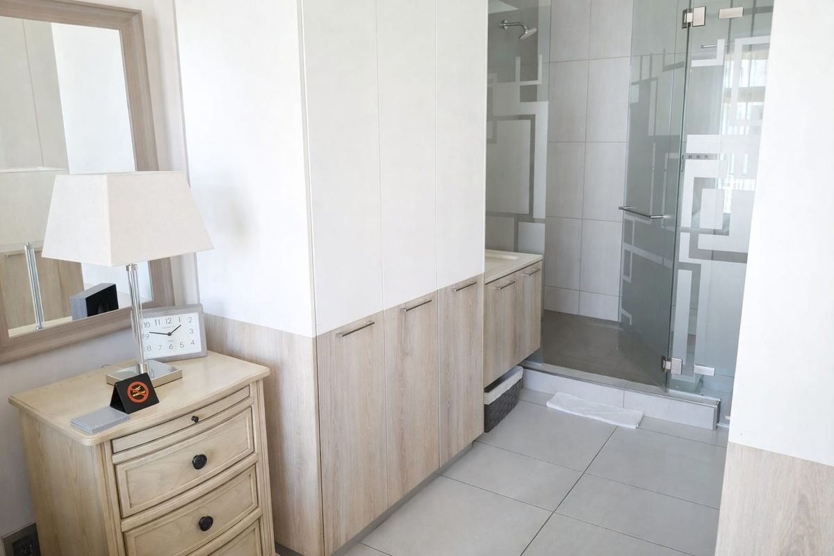 Modern bathroom featuring built-in cabinetry, a glass-enclosed shower, and neutral tiled finishes, offering a clean and functional space.