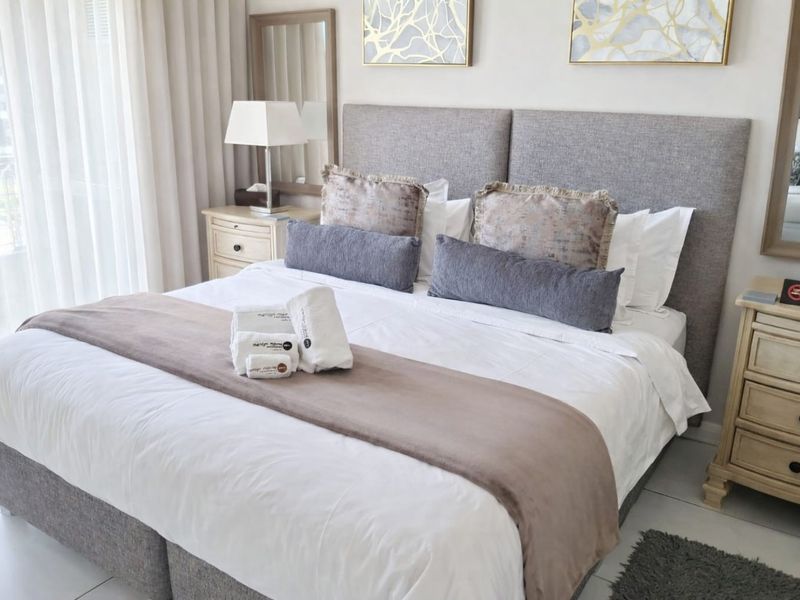 A well-maintained bedroom featuring tiled flooring and a large sliding glass door with sheer curtains, providing ample natural light.