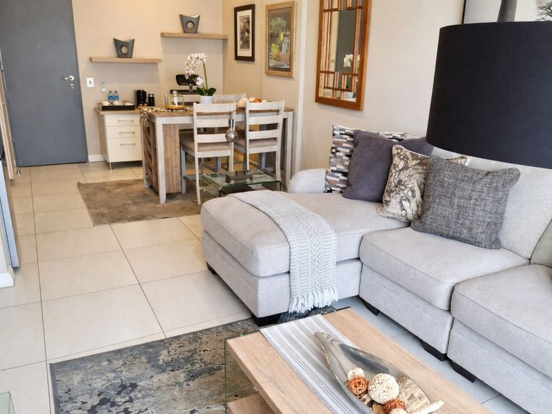 An open-plan living and dining area featuring neutral tiled flooring and modern floating shelves, creating a bright and functional living space.