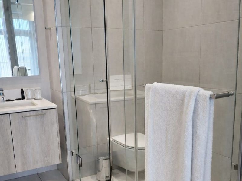 Modern bathroom featuring a wall-mounted vanity with integrated basin, a glass-enclosed shower, and a wall-hung toilet with concealed cistern.