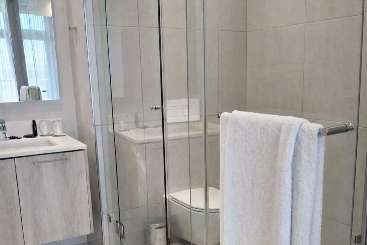 Modern bathroom featuring a wall-mounted vanity with integrated basin, a glass-enclosed shower, and a wall-hung toilet with concealed cistern.