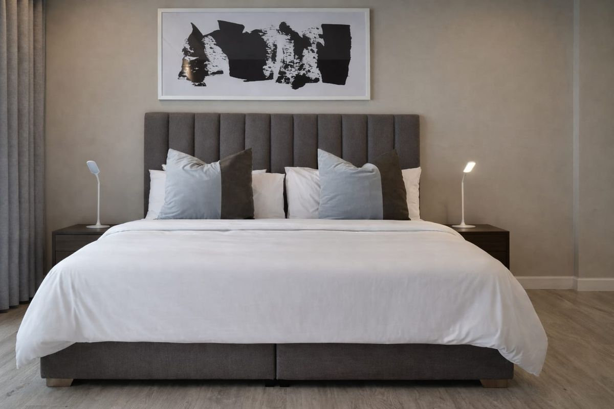 A well-appointed bedroom featuring neutral wall tones, modern laminate flooring, and floor-to-ceiling curtains, creating a clean and contemporary living space.
