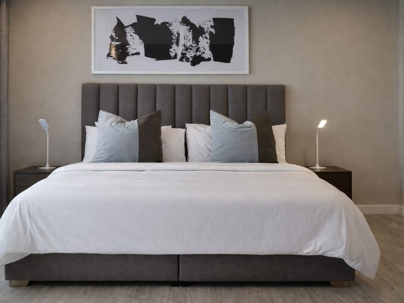 A well-appointed bedroom featuring neutral wall tones, modern laminate flooring, and floor-to-ceiling curtains, creating a clean and contemporary living space.