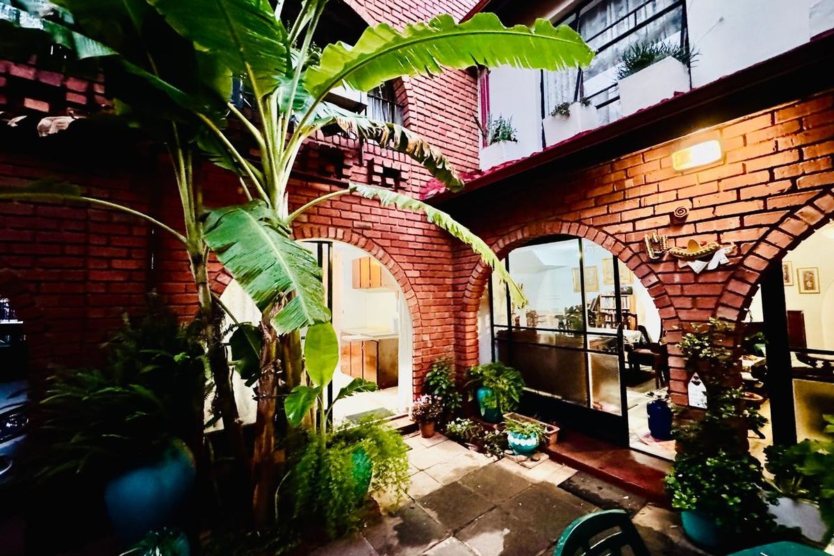 A charming rear courtyard featuring exposed brickwork, arched architectural details, and a paved patio area connecting to the interior living spaces.