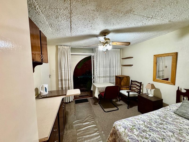 Open-plan living and kitchen area featuring a ceiling fan, built-in cabinetry, and direct access to an outdoor patio space.