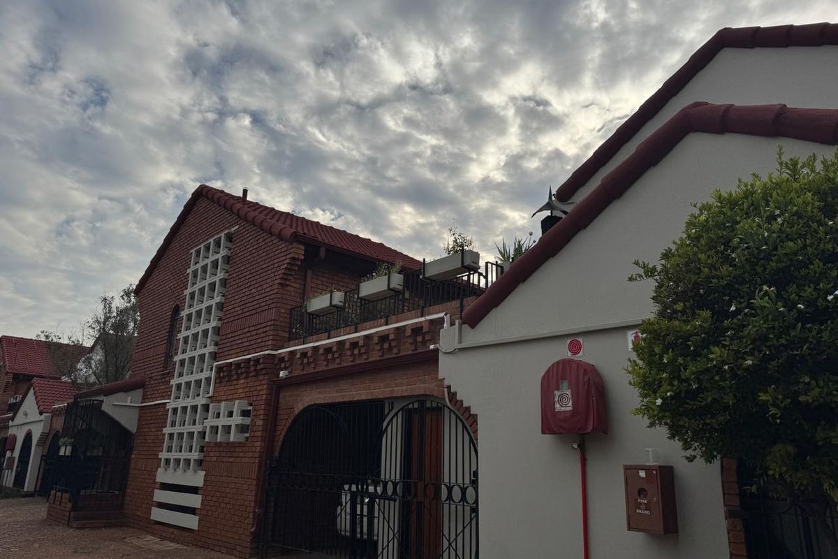 Front elevation of a brick apartment building featuring a balcony, secure gated entrance, and integrated fire safety equipment.