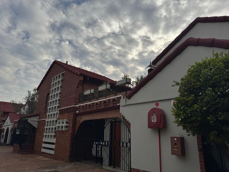 Front elevation of a brick apartment building featuring a balcony, secure gated entrance, and integrated fire safety equipment.