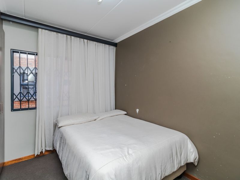 A bedroom featuring a built-in wardrobe, security gate on the window, and neutral wall finishes.