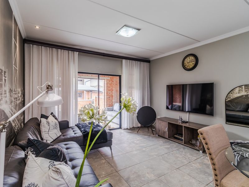 A well-maintained living room featuring tiled flooring, recessed lighting, and a sliding glass door providing access to an outdoor patio area.