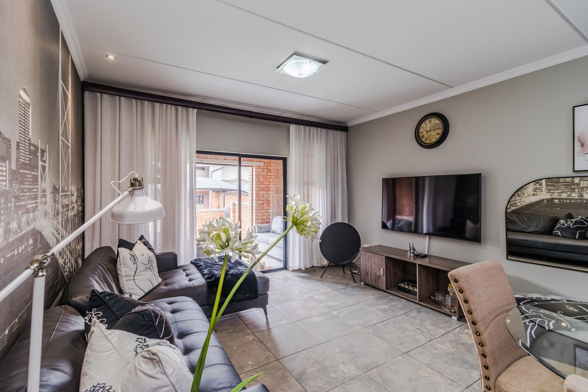 A well-maintained living room featuring tiled flooring, recessed lighting, and a sliding glass door providing access to an outdoor patio area.