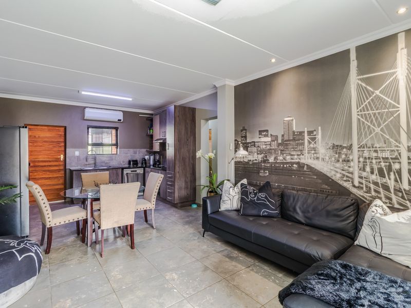 Open-plan living and kitchen area featuring tiled flooring, built-in cabinetry, and a wall-mounted air conditioning unit.