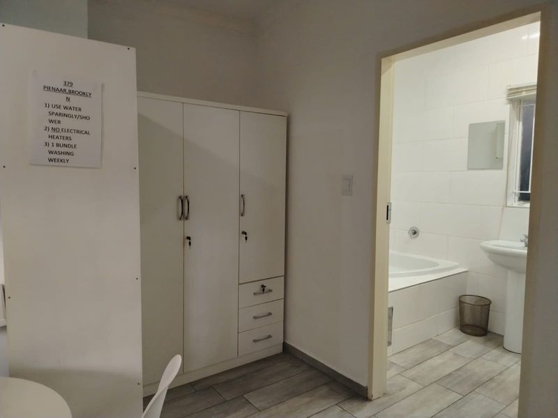 Bedroom featuring a built-in wardrobe and direct access to an en-suite bathroom with a bathtub and pedestal basin.