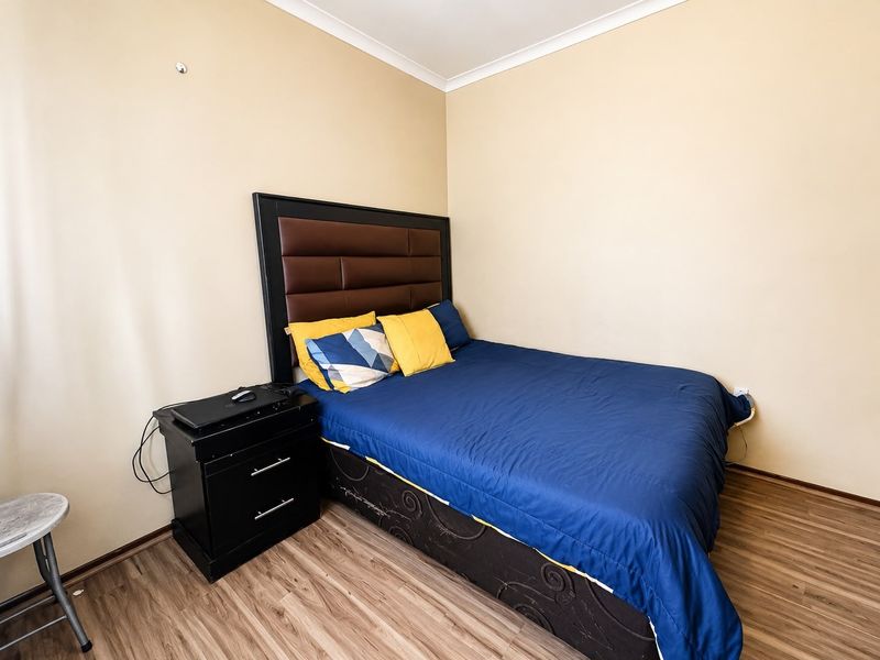 A standard bedroom featuring laminate flooring and neutral wall paint, providing a functional and clean sleeping space.