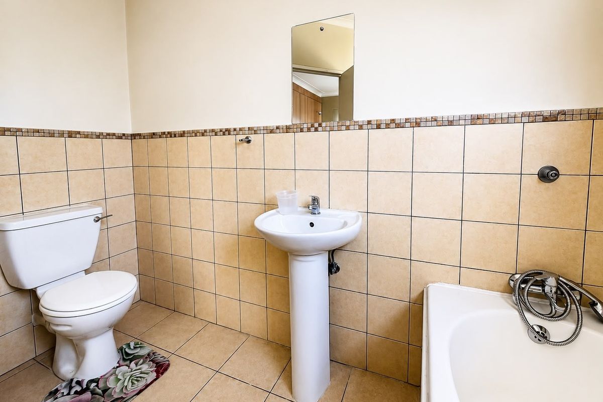 A functional bathroom featuring a pedestal basin, toilet, and bathtub with tiled walls and flooring throughout.