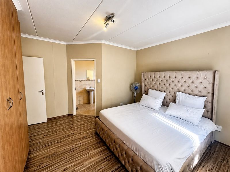 A well-maintained bedroom featuring laminate flooring, built-in wardrobe storage, and direct access to an en-suite bathroom.