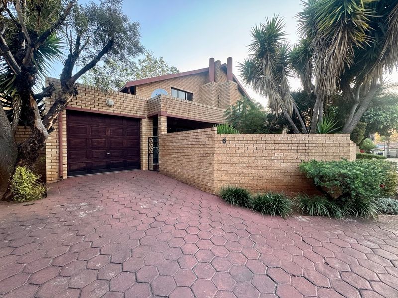 Front exterior view of a brick townhouse featuring a paved driveway, integrated garage, and established garden boundary wall.