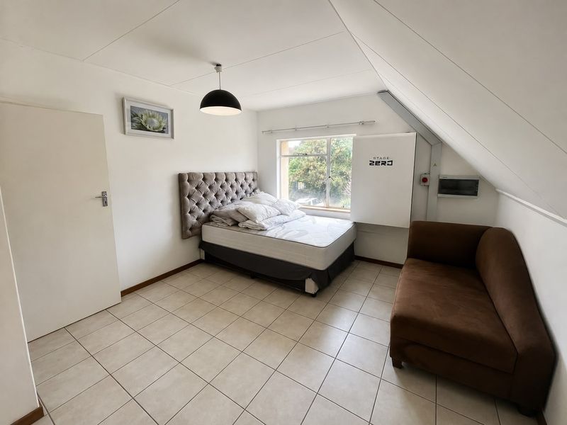 A bedroom featuring tiled flooring, a sloped ceiling, and integrated solar battery storage infrastructure.
